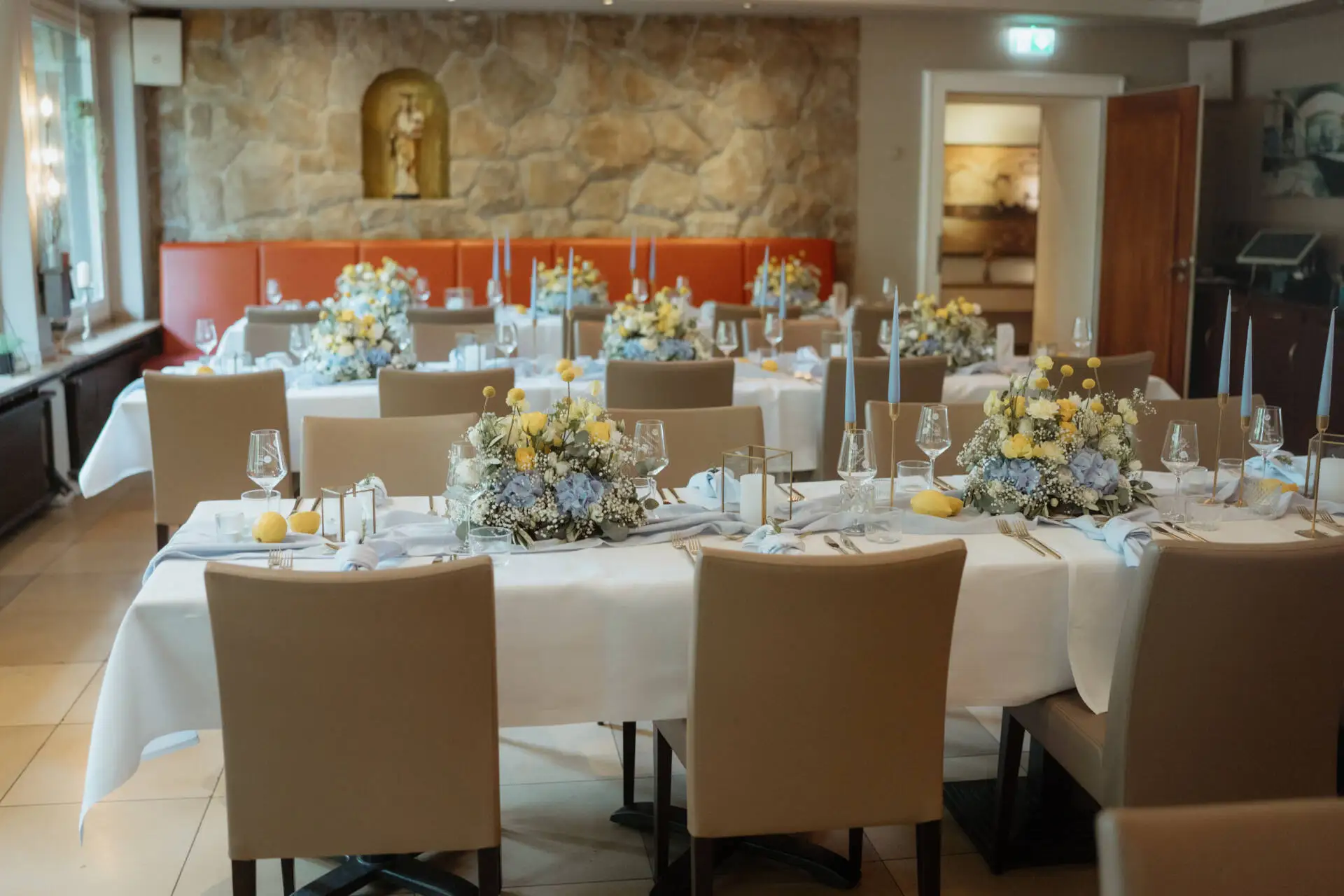 Festlich gedeckter Saal mit Blumenschmuck und Kerzen.