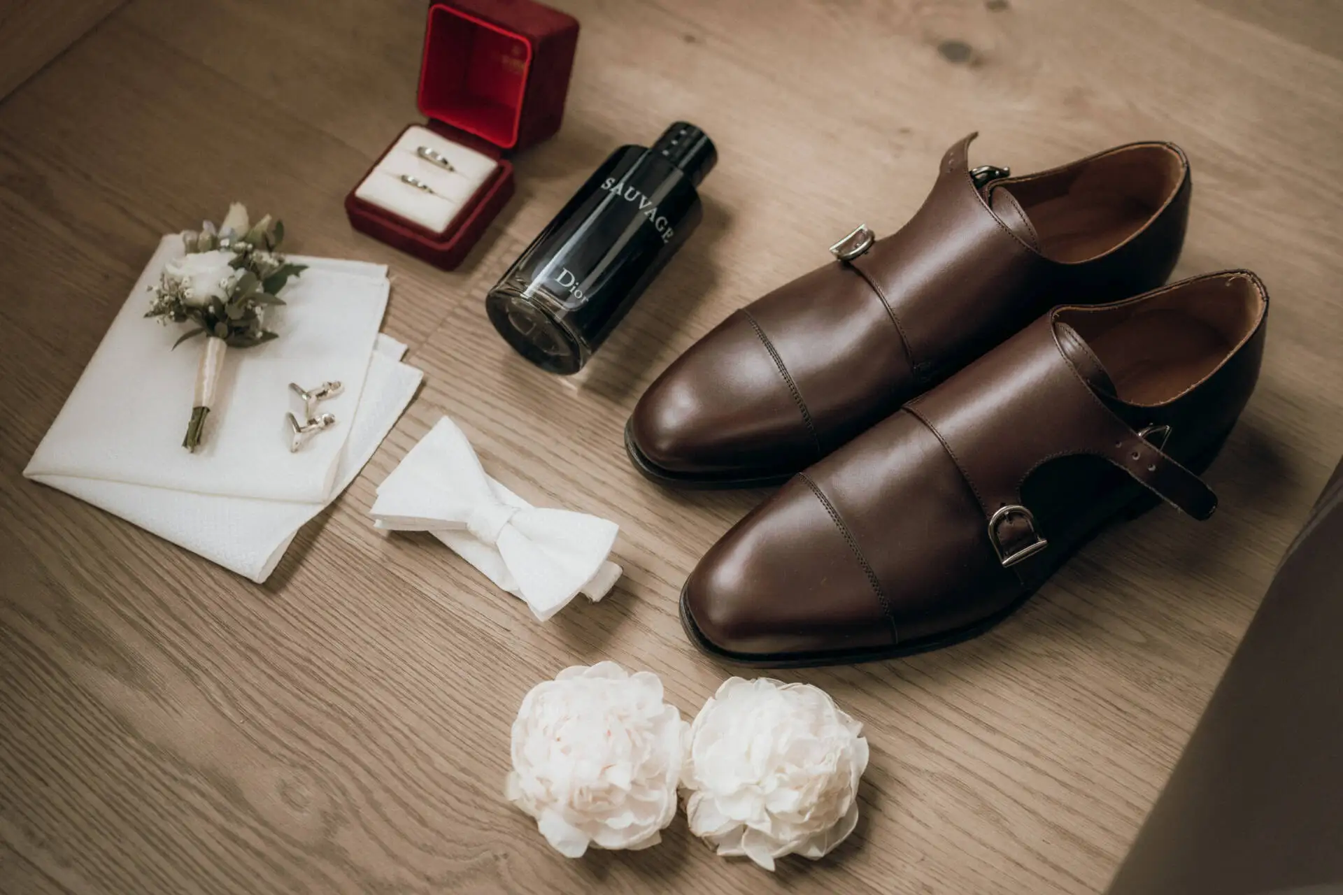 Brautaccessoires und braune Hochzeitsschuhe auf Holzboden.