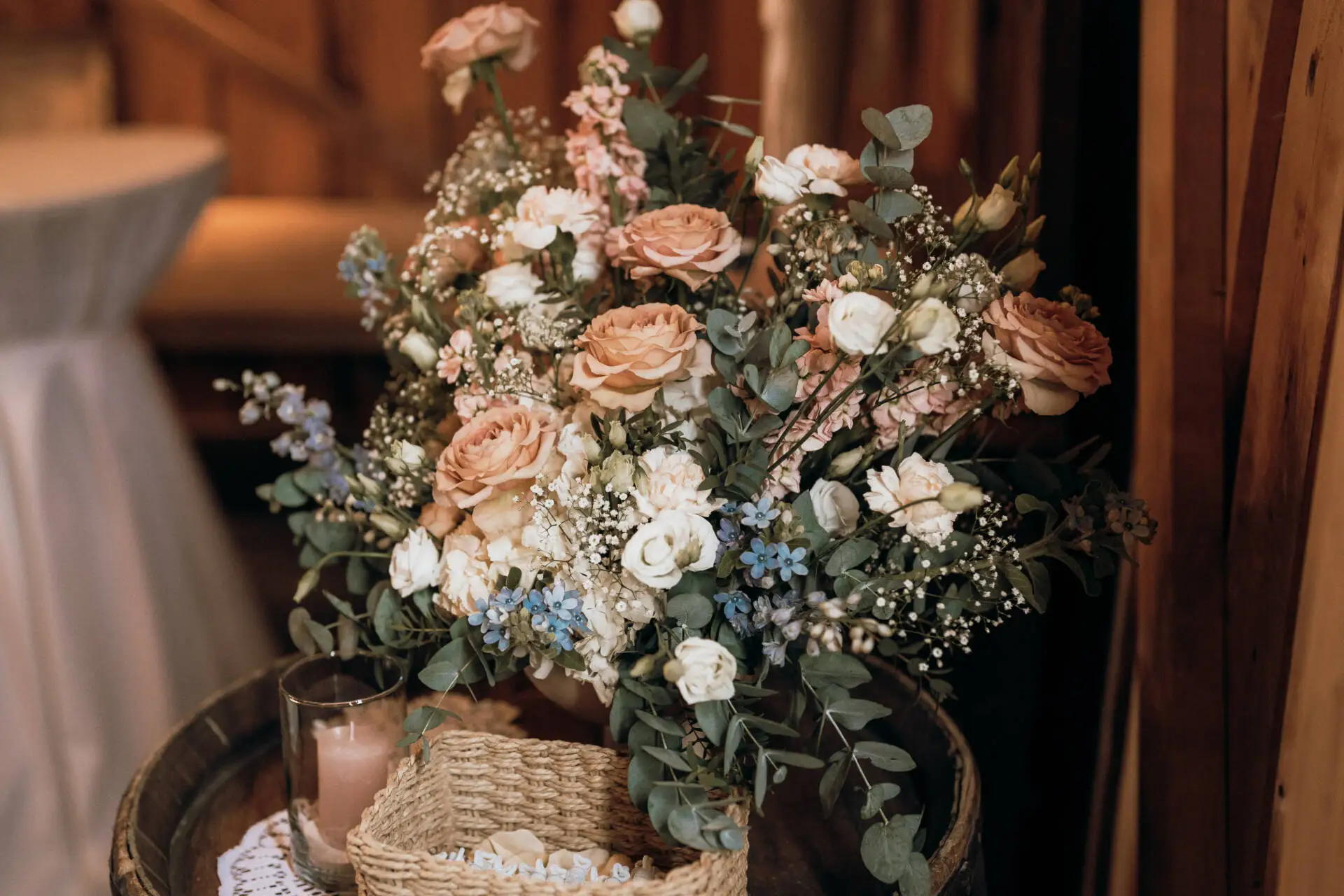 Blumenarrangement mit Rosen auf Holztisch.