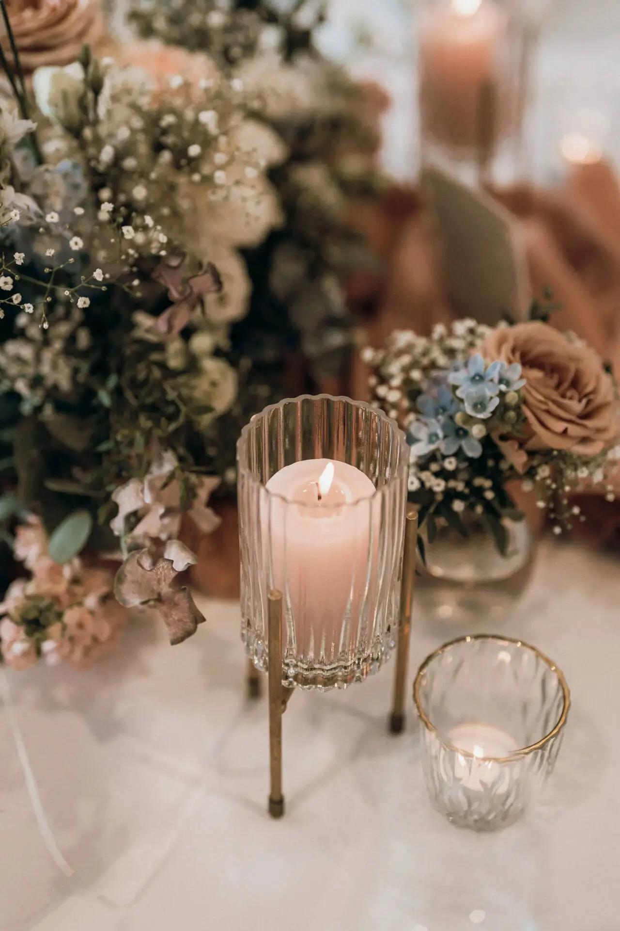 Kerze mit Blumenarrangement auf Tisch