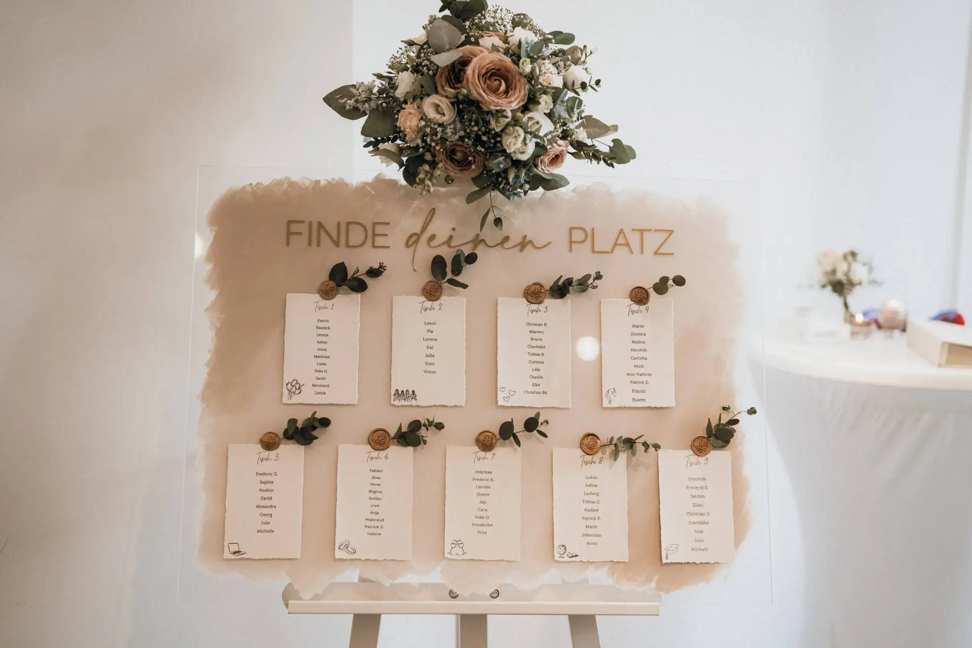 Hochzeits-Sitzplan mit Tischkarten und Blumenbouquet.