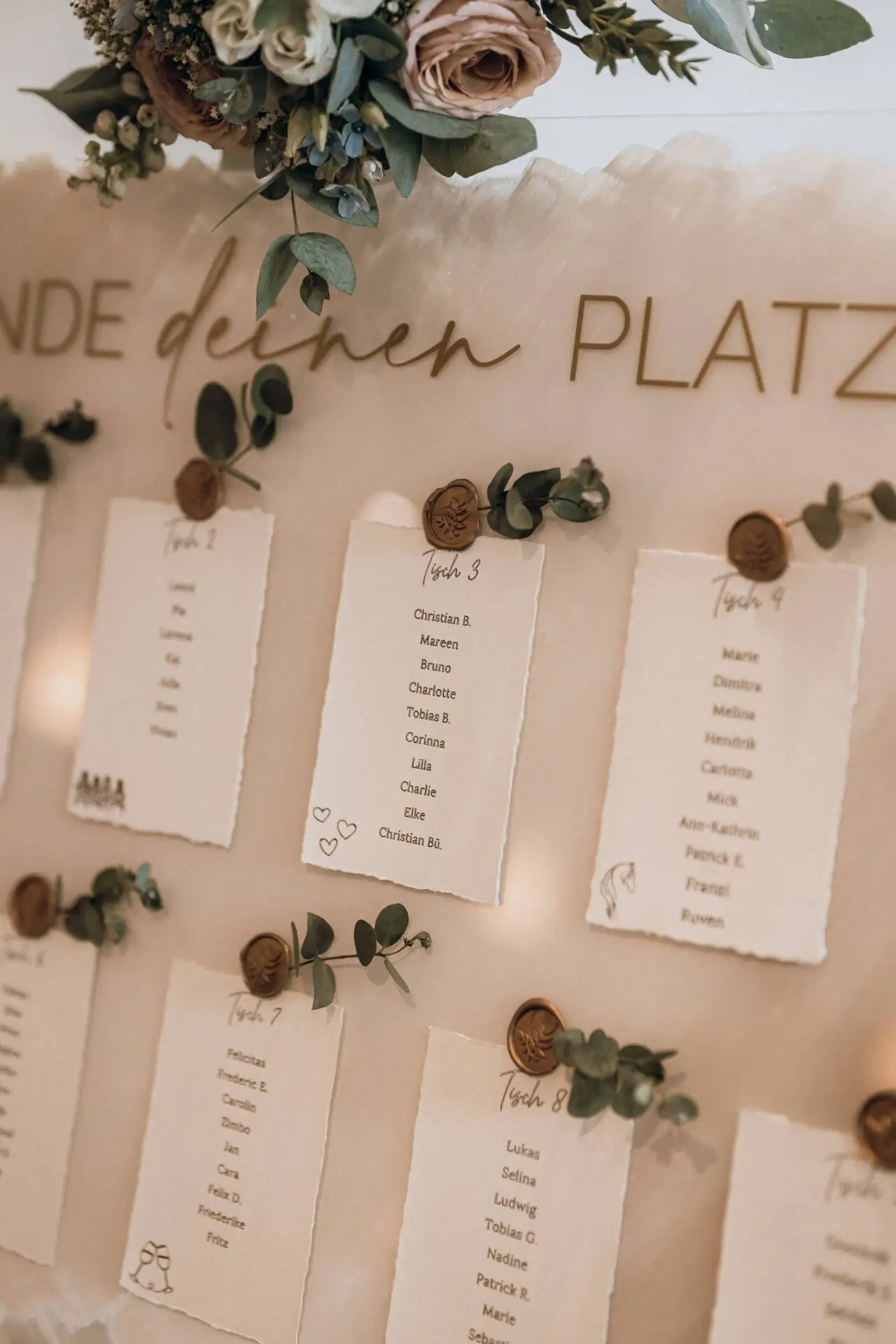 Hochzeits-Sitzplan mit Blumen und Wachsiegeln.