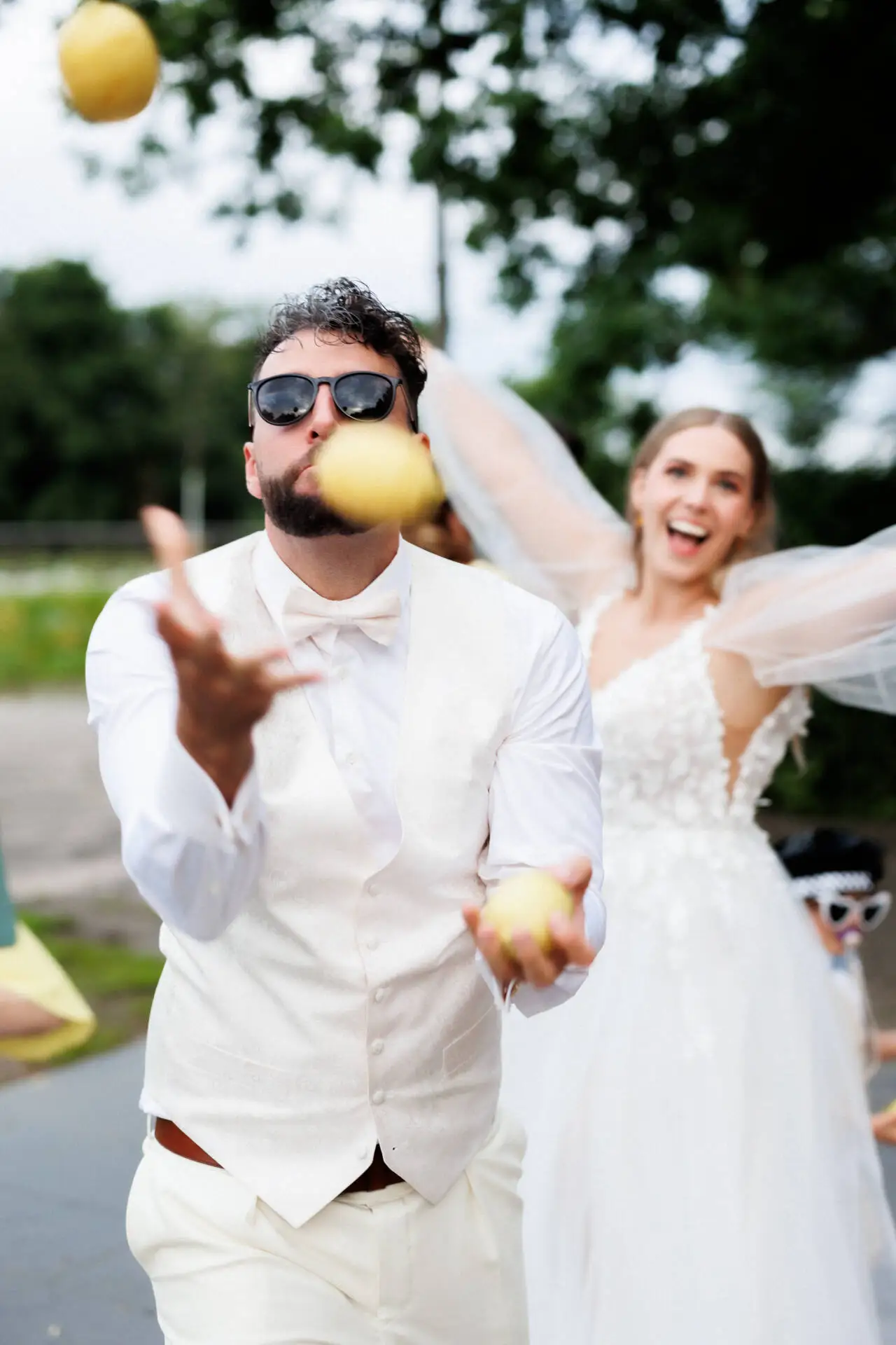 Bräutigam jongliert Zitronen vor Hochzeitskleid-Braut.
