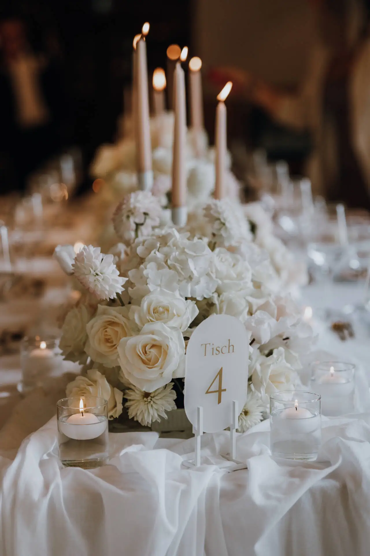 Tischdekoration mit weißen Blumen und Kerzen.