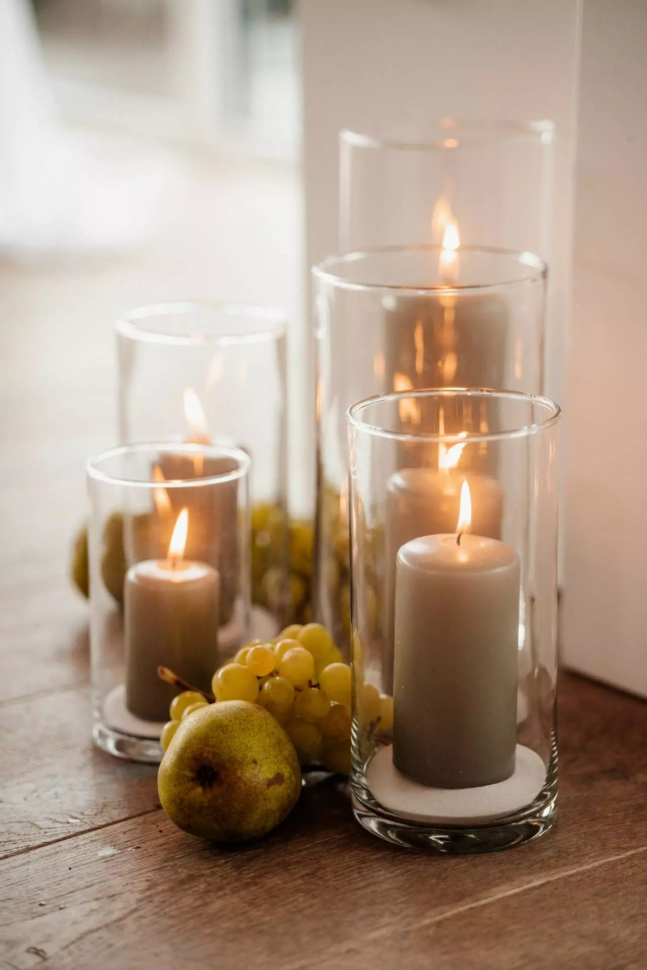 Kerzen mit Trauben und Birne auf Holzboden
