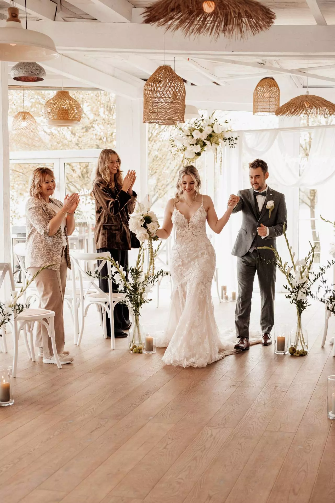 Brautpaar im Hochzeitskleid und Anzug, Gäste applaudieren.