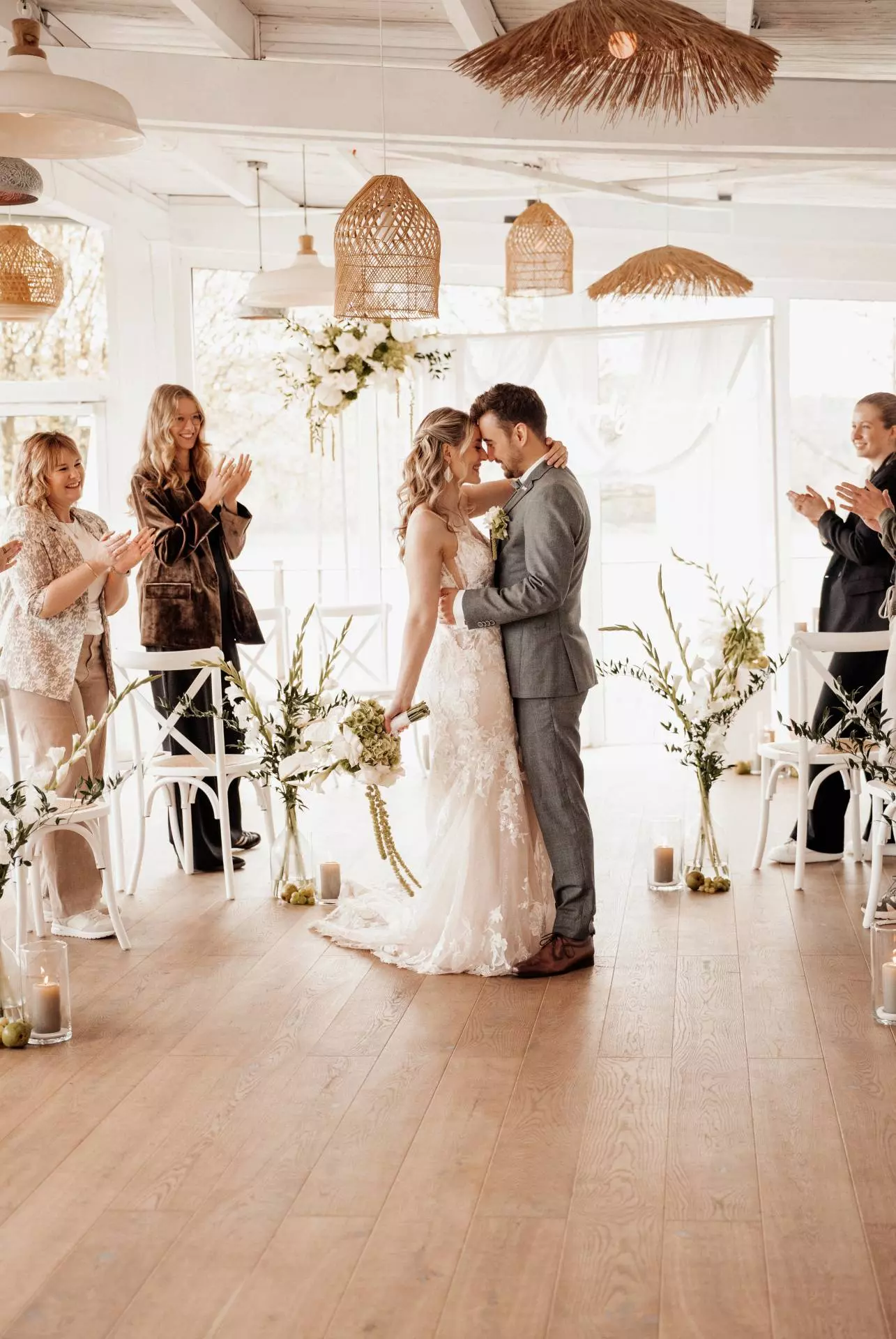 Hochzeitspaar küsst sich bei Zeremonie, Gäste applaudieren.