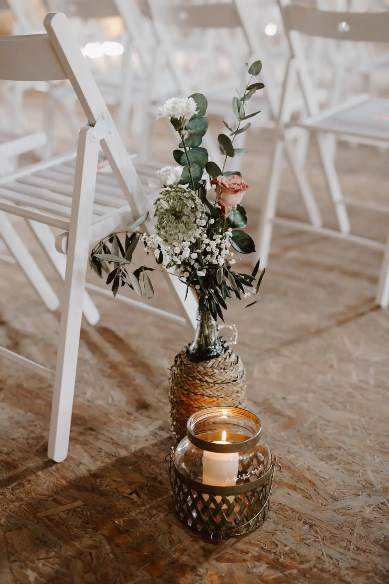Kerze und Blumen bei Stühlen auf Holzboden