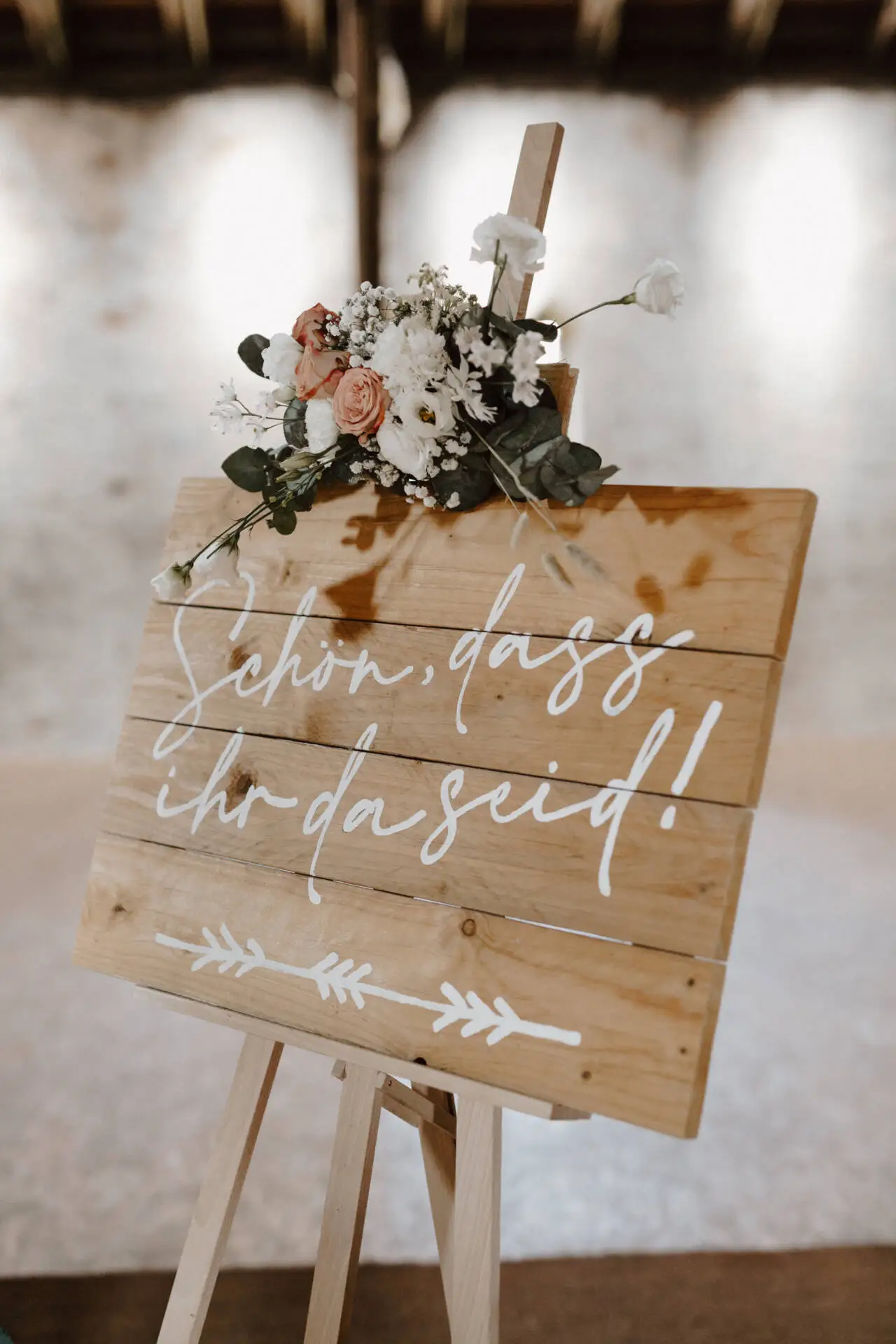 Hochzeitsdekoration mit Willkommensschild und Blumen