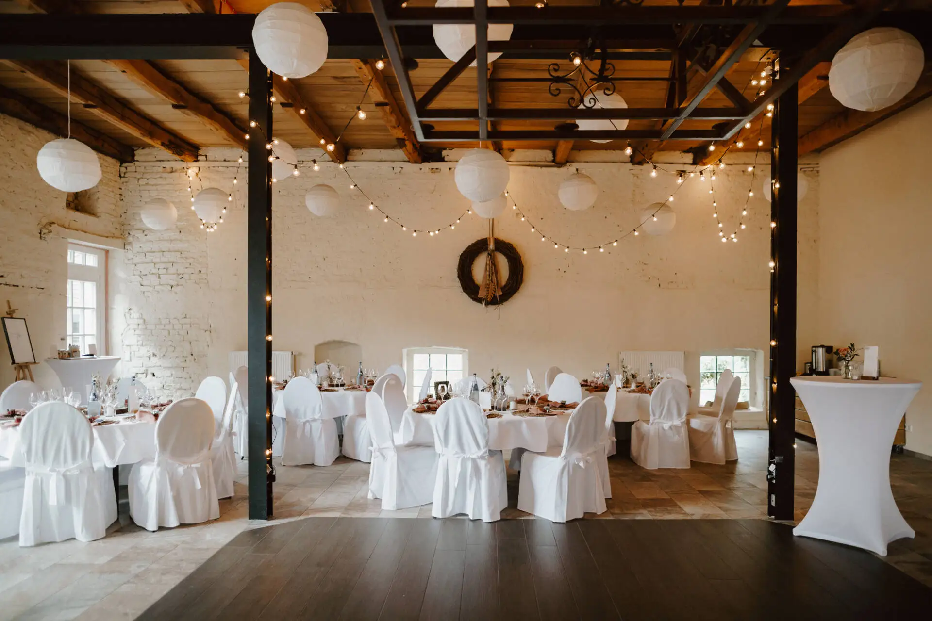 Hochzeitslokation mit festlich gedeckten Tischen und Dekorationen.