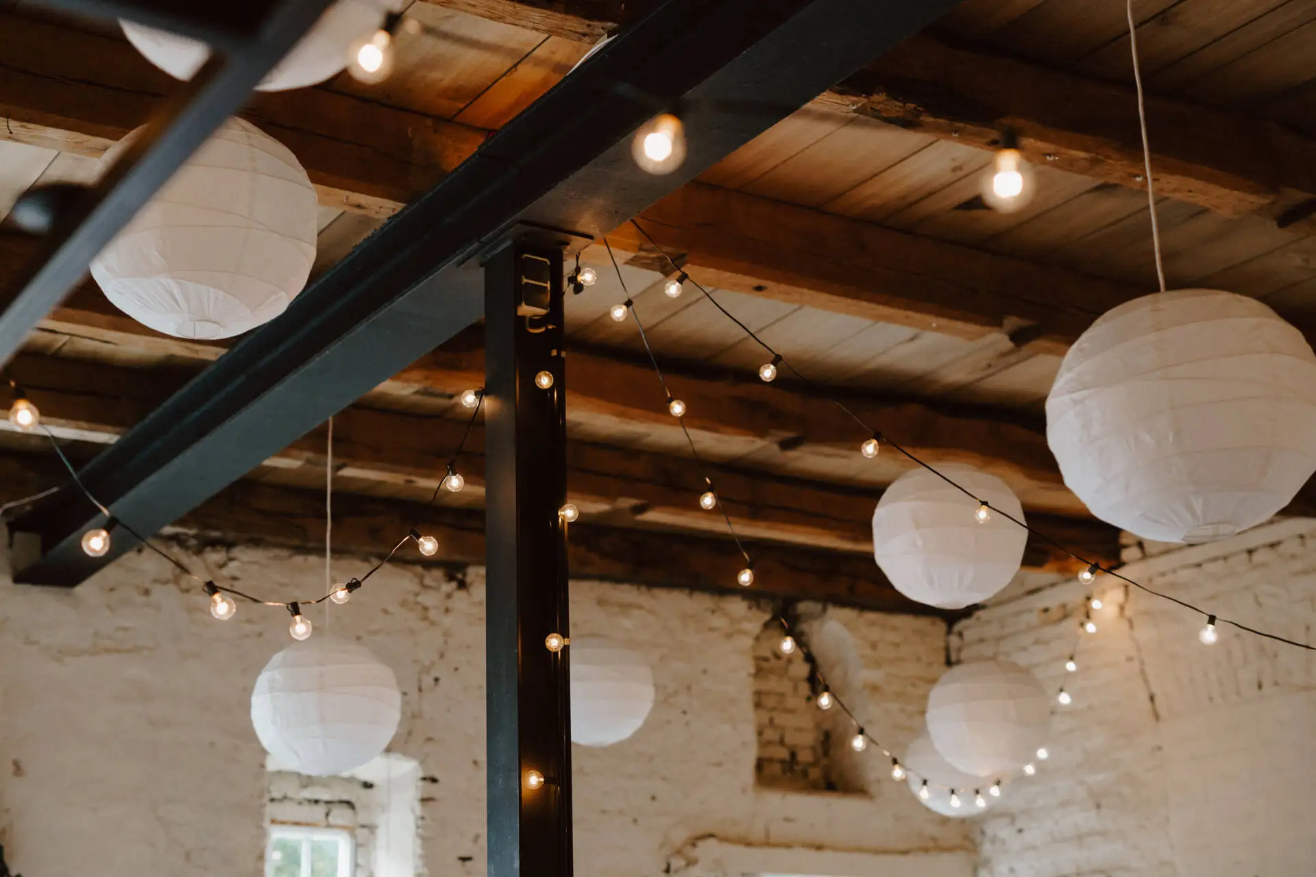Lichterketten und Papierlampen in rustikalem Raum