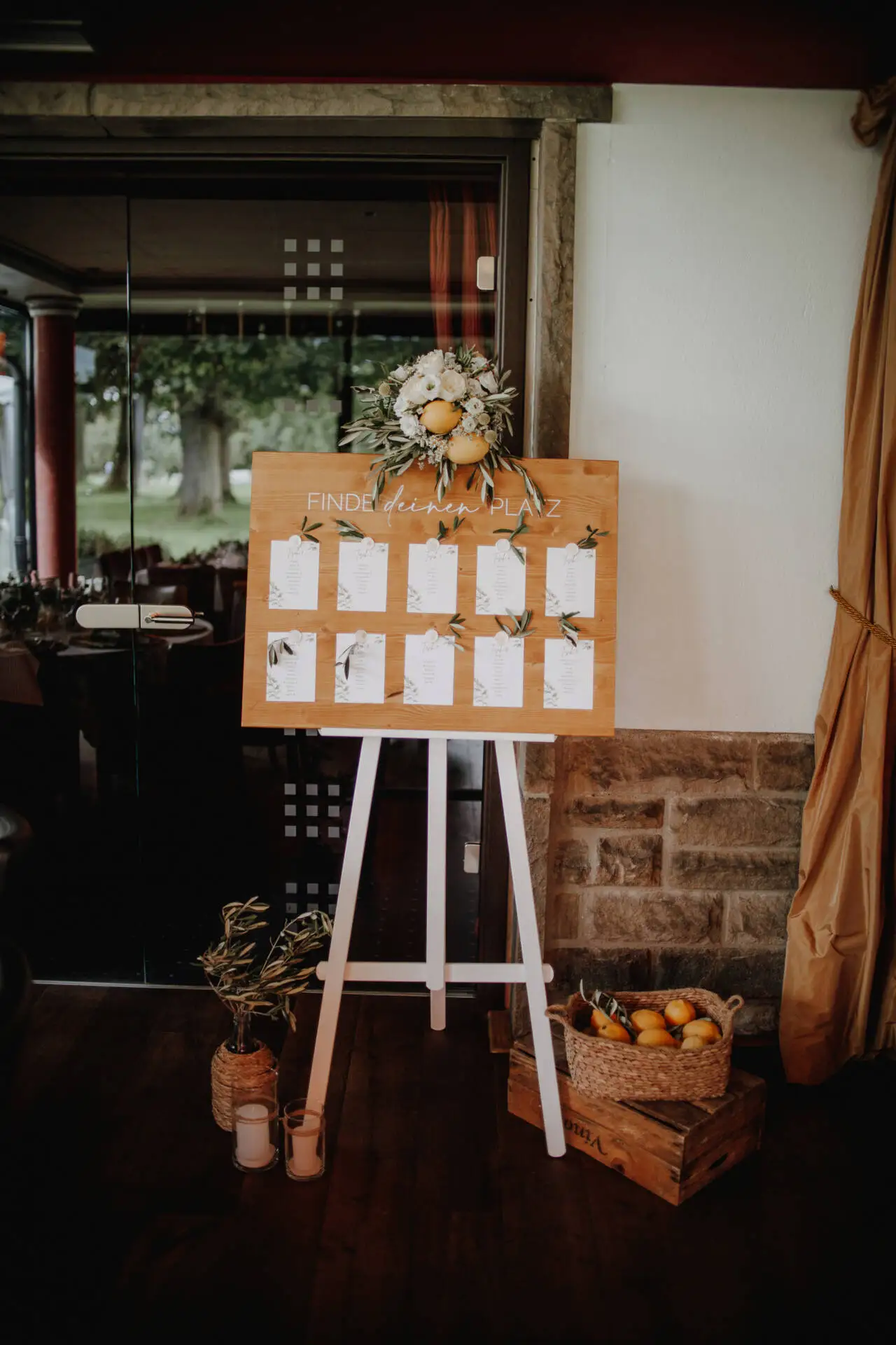 Hochzeitssitzplan auf Staffelei mit Blumen und Zitronen.