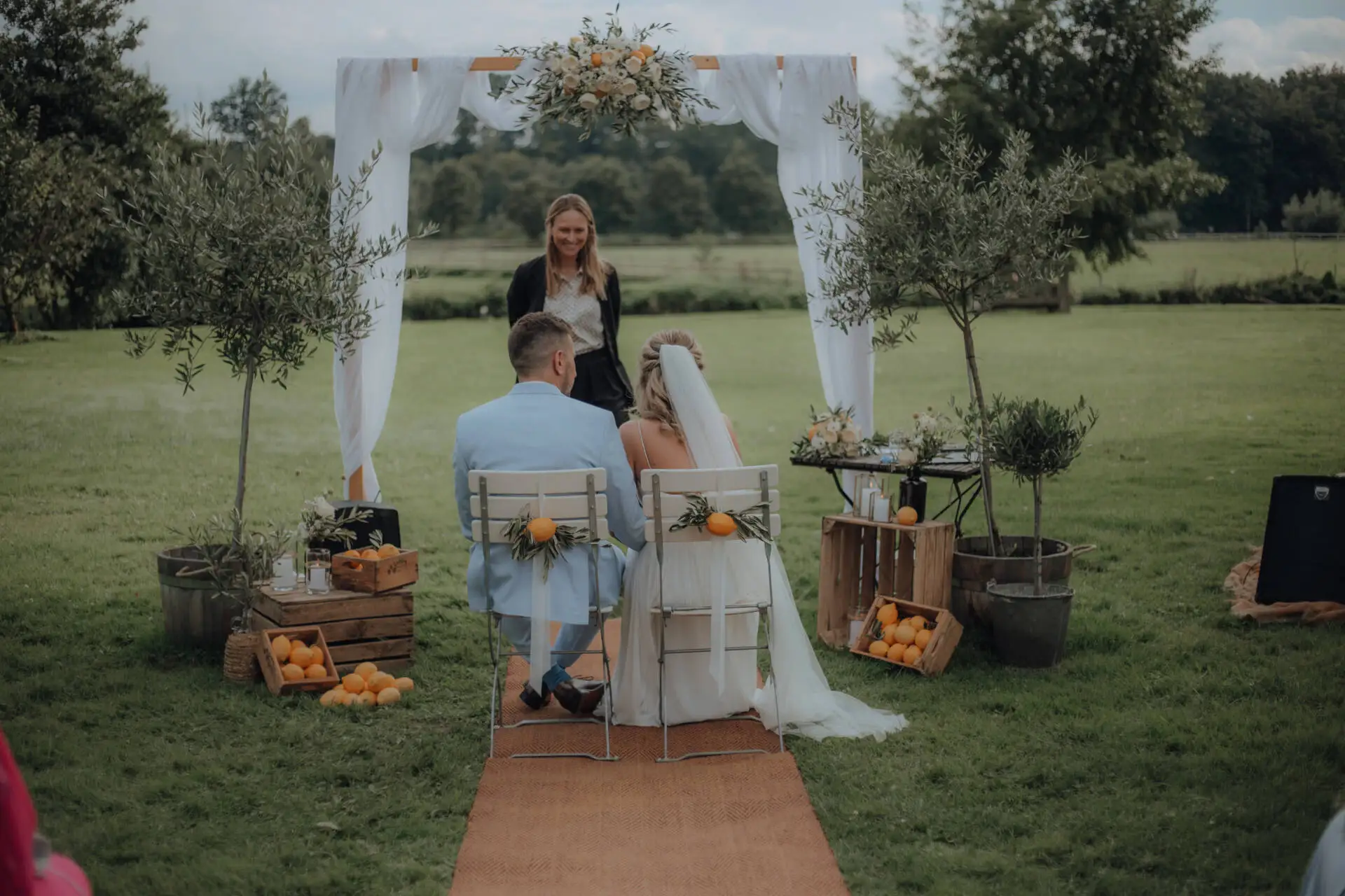 Hochzeit im Freien mit dekorierten Stühlen und Bäumen.