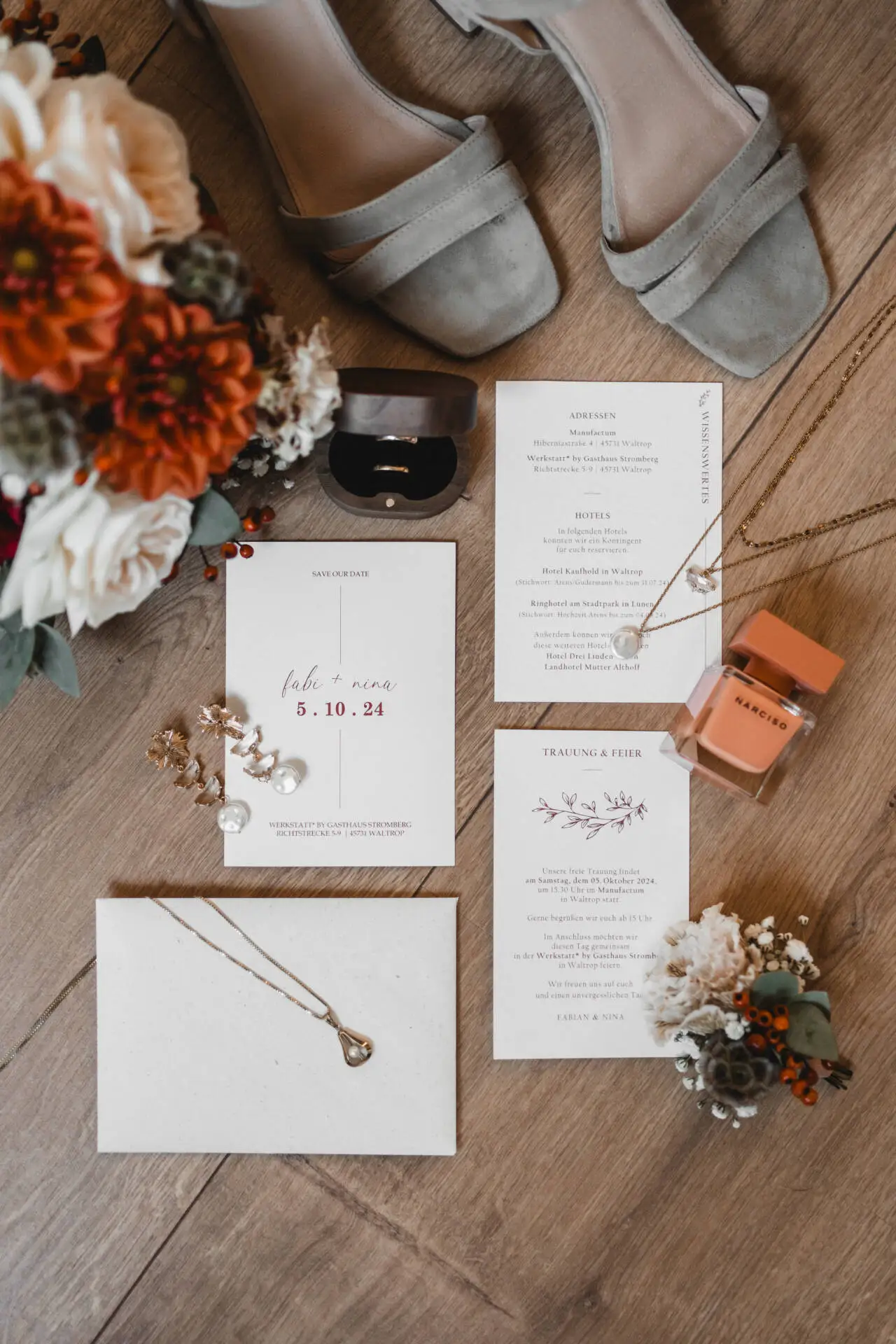 Hochzeitseinladung mit Accessoires und Blumen auf Holzboden