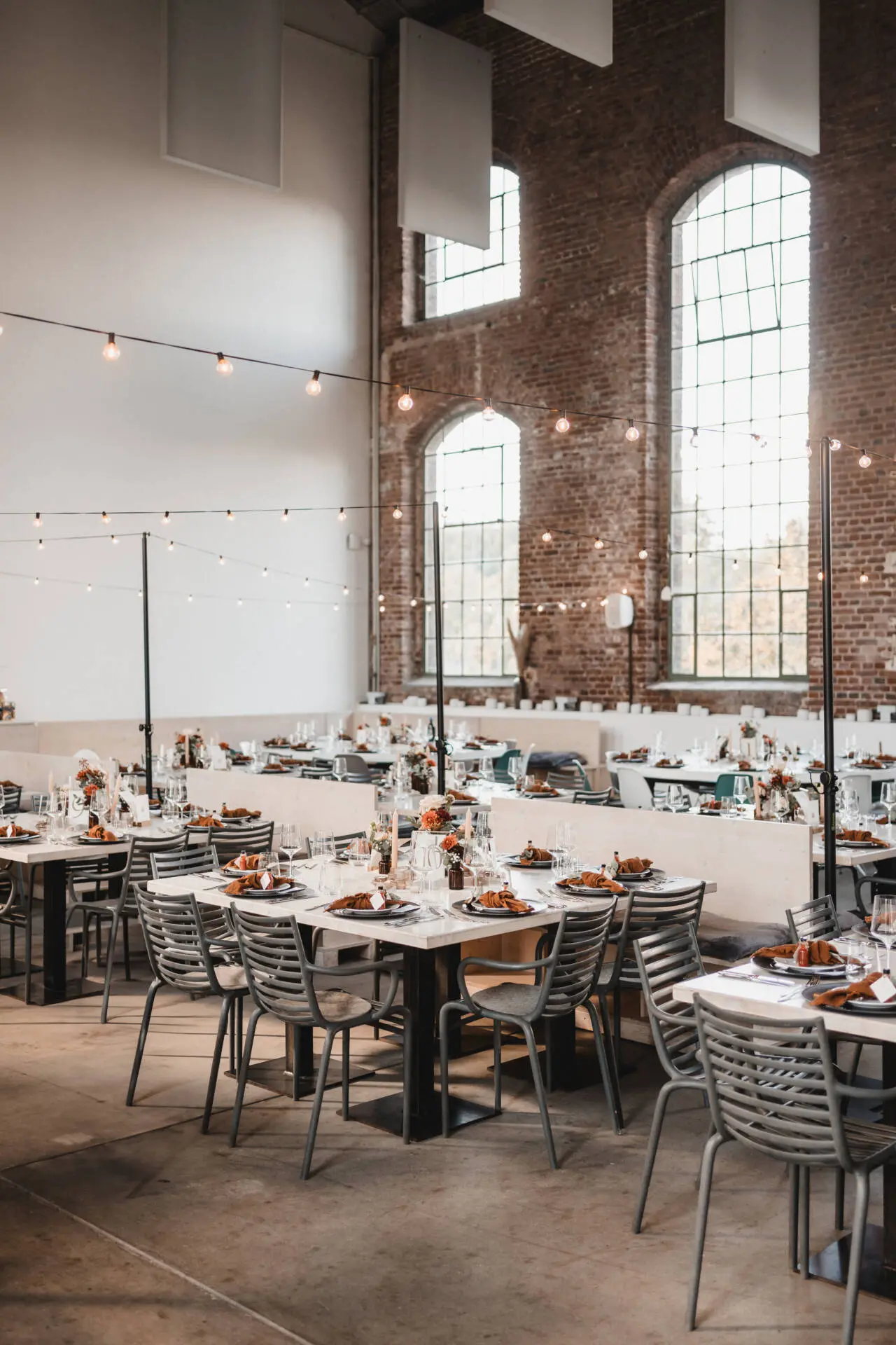 Industrielles Restaurant mit gedeckten Tischen und Lichterketten.