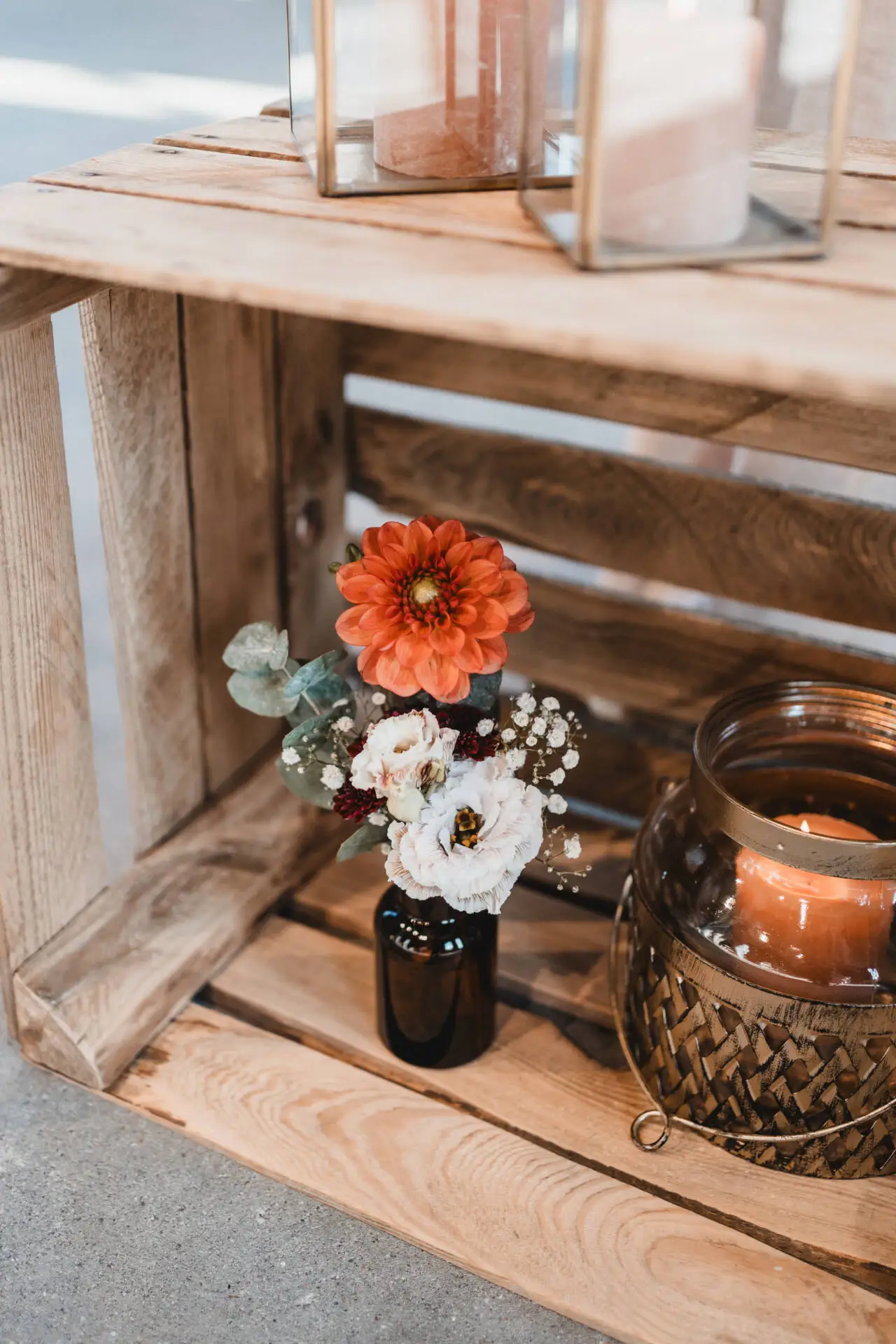 Blumenarrangement im Holzkasten mit Kerze