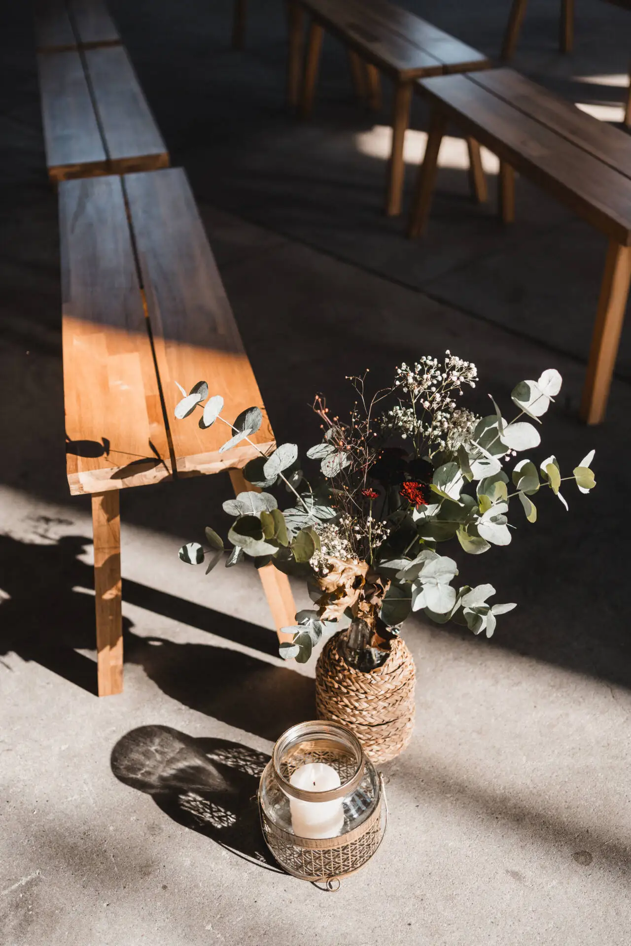 Holzbank mit Pflanze und Kerze im Sonnenlicht