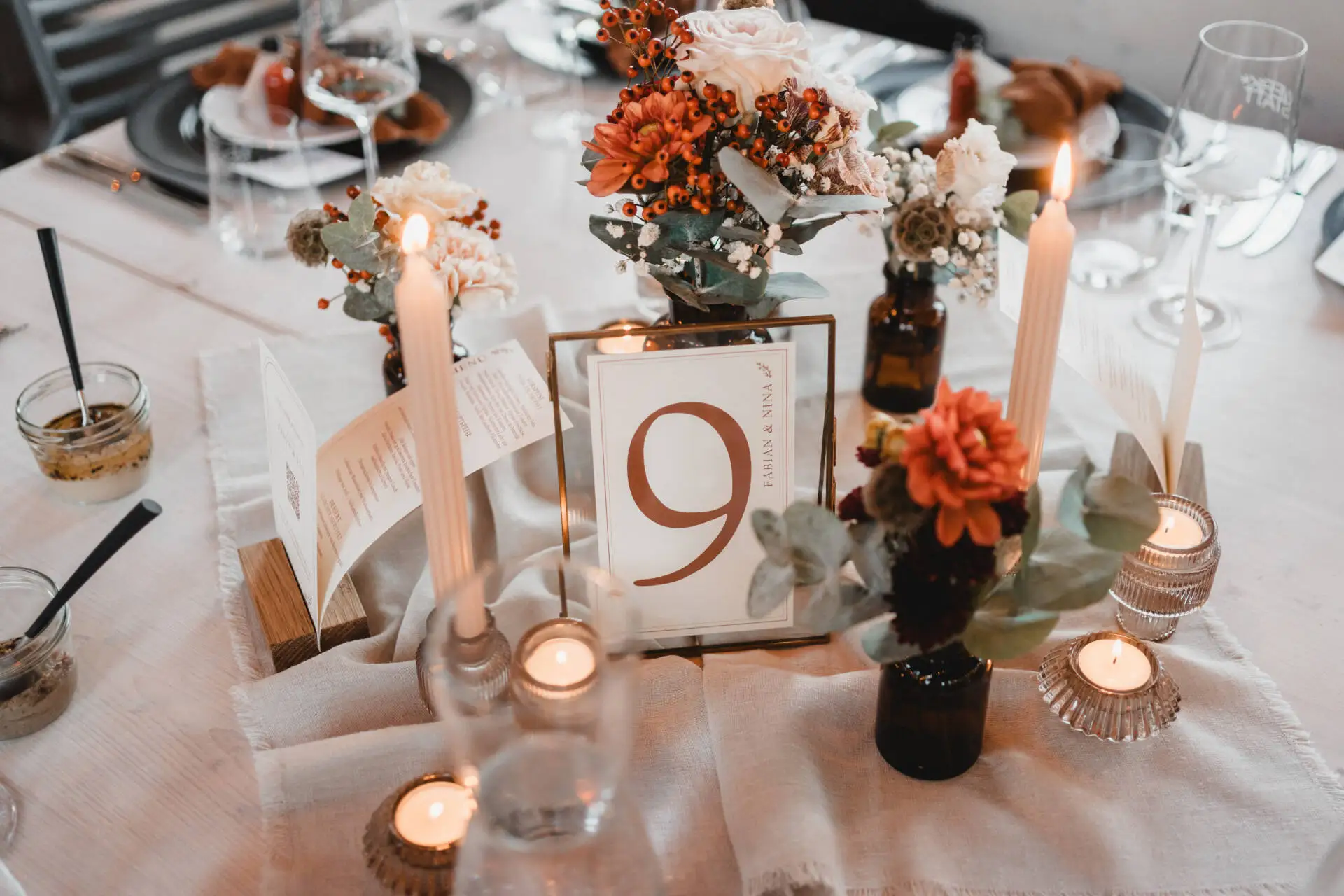 Elegant gedeckter Tisch mit Blumen und Kerzen.