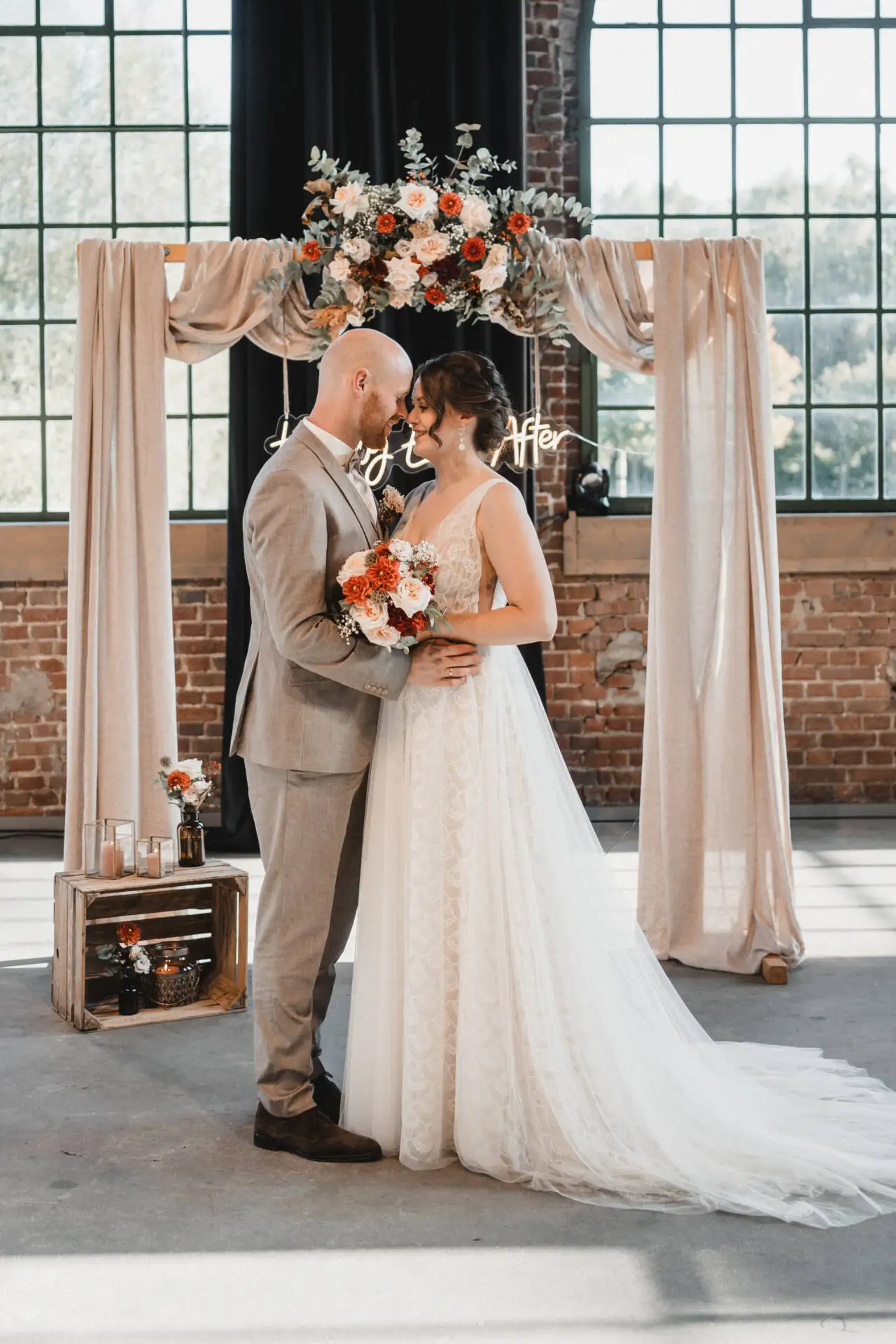 Hochzeitspaar unter Blumenbogen in rustikaler Umgebung
