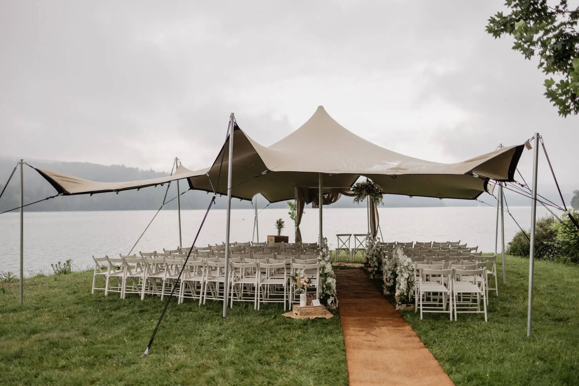 Hochzeitszelt am See mit Stühlen und Blumen