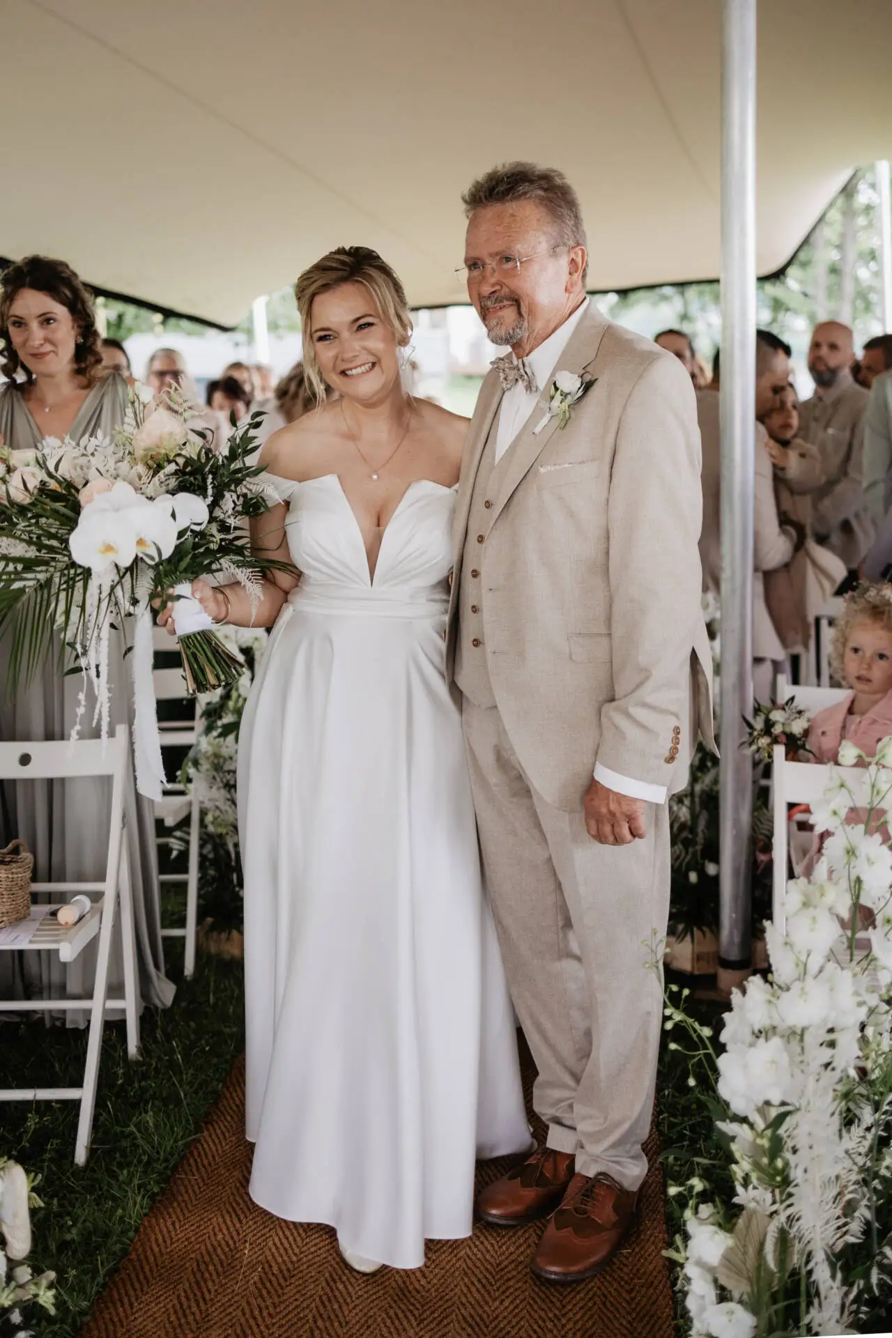 Braut und Vater lächeln bei Hochzeitszeremonie.