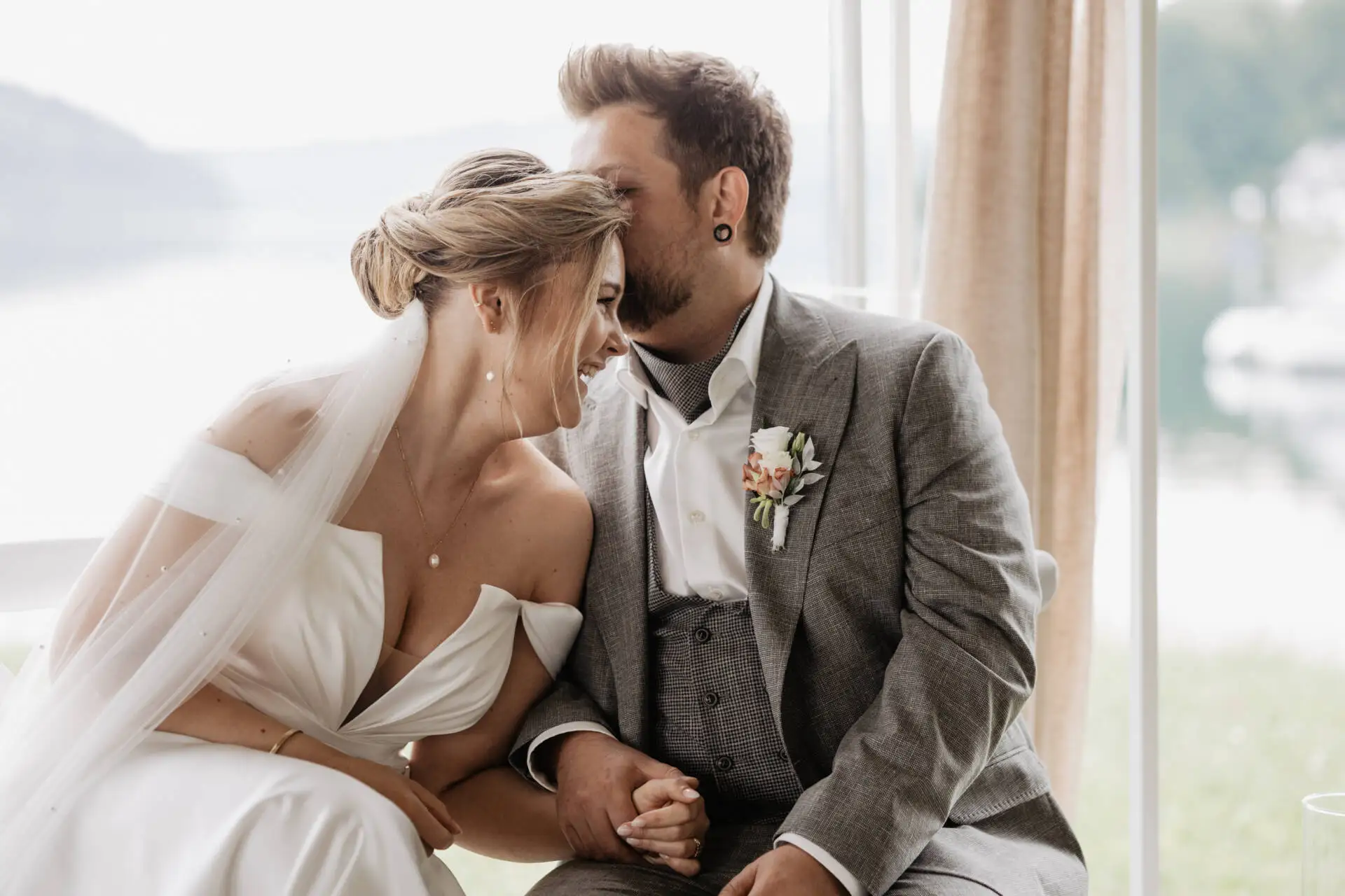 Frisch vermähltes Hochzeitspaar lächelt und hält sich Händchen.